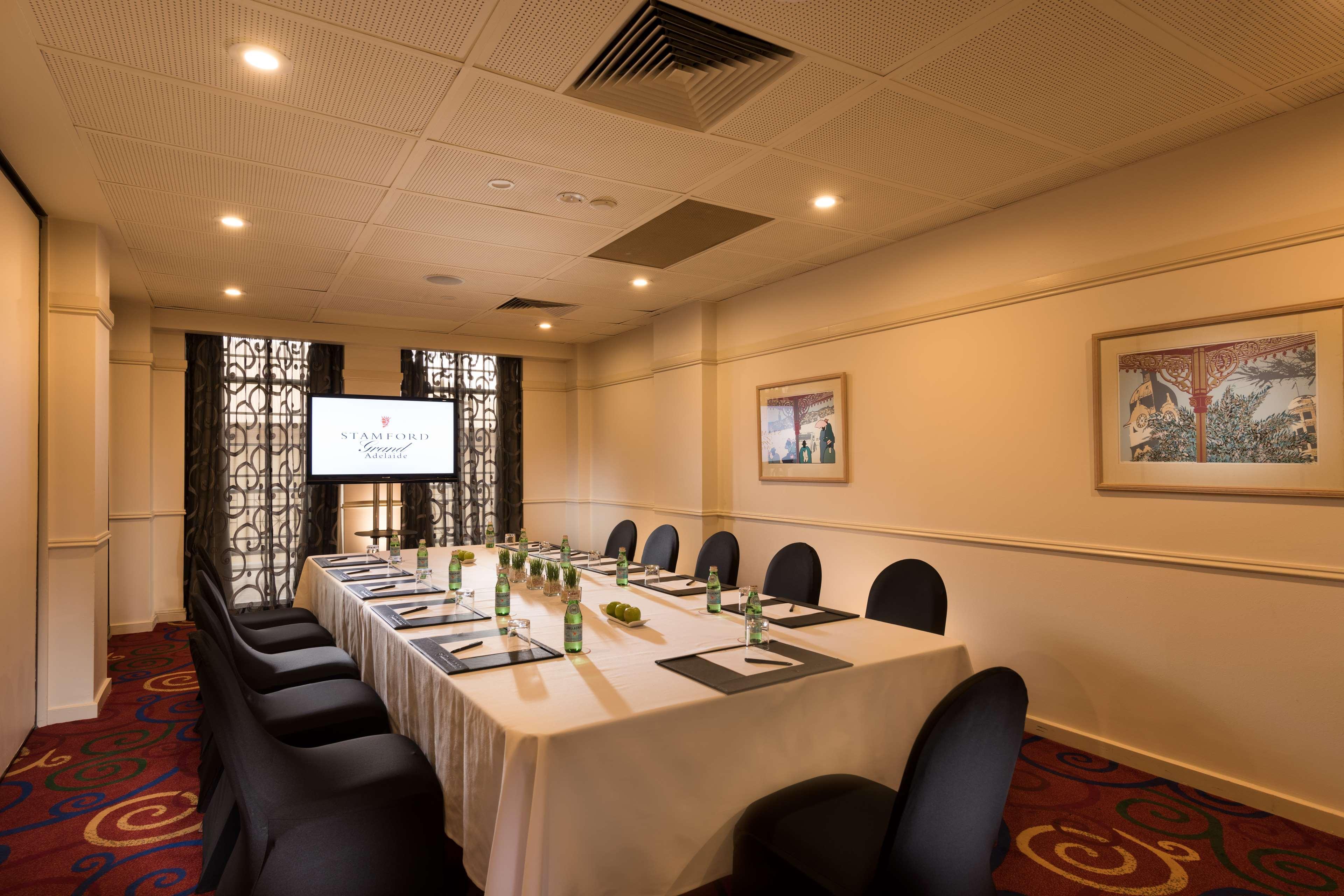 Stamford Grand Adelaide Hotel Glenelg Eksteriør billede The photo shows a conference room with a long rectangular table set for a meeting. The table is covered with a white tablecloth and has several place settings, including notebooks, pens, and water bottles. There are black chairs around the table, and