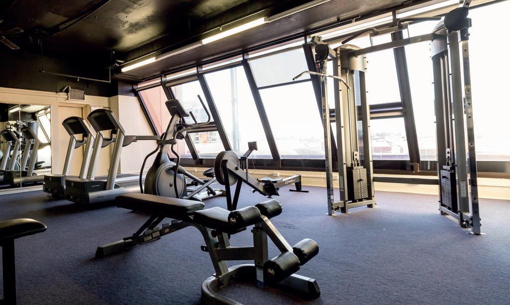 Stamford Grand Adelaide Hotel Glenelg Eksteriør billede The photo shows a modern gym interior with several exercise machines. There are cardio machines, likely including treadmills and possibly an elliptical machine, along one side. In the center, there is a weight bench and a rowing machine. Additionally